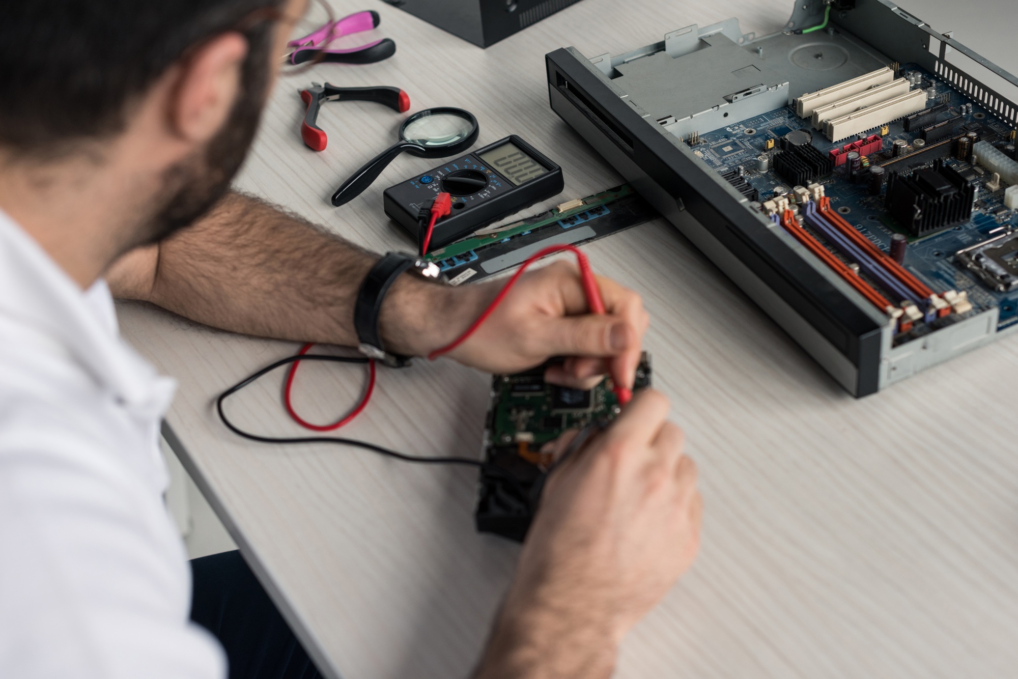 cropped image of man using multimeter while testing hard disk drive